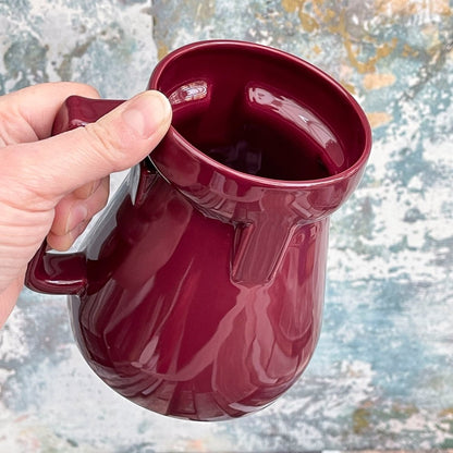 A hand holds a dark red Raktajino replica mug, evoking imagery from Quark's Bar on DS9 and referencing Klingon coffee.
