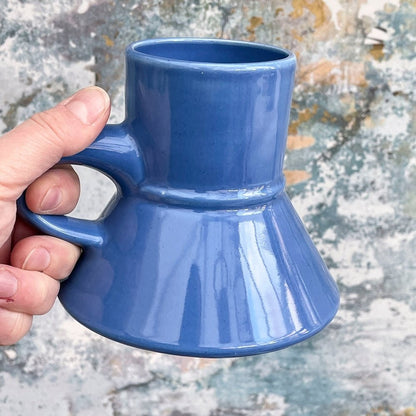 A hand holds a blue Replimat mug resembling those used for Raktajino and Tarkalean Tea on Star Trek: Deep Space Nine.
