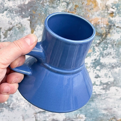 A hand holds a blue Replimat mug, resembling those used for Raktajino and Tarkalean tea in Star Trek: Deep Space Nine (DS9).