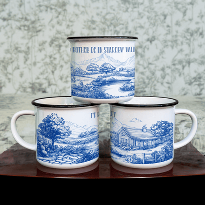Three blue and white enamel camping cups feature a chinoiserie-style landscape design inspired by the computer game Stardew Valley, with one cup reading "I'd Rather Be In Stardew Valley.