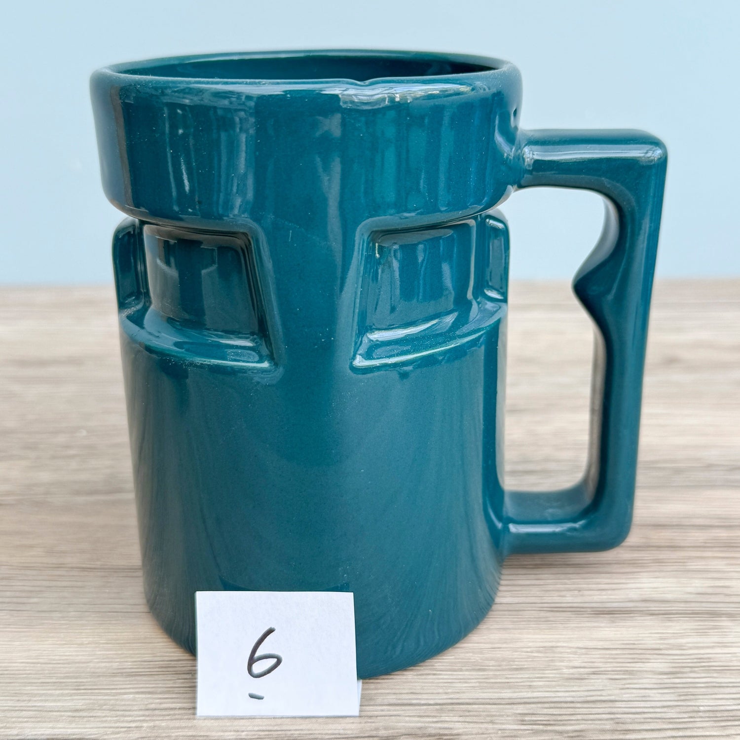 A handmade "Rejected Raktajino Mug" by Quirkify, sitting on a wooden surface. Give one a good home today!.