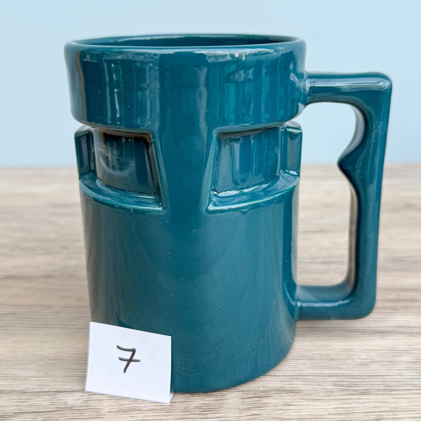 A handmade "Rejected Raktajino Mug" by Quirkify, sitting on a wooden surface. Give one a good home today!.