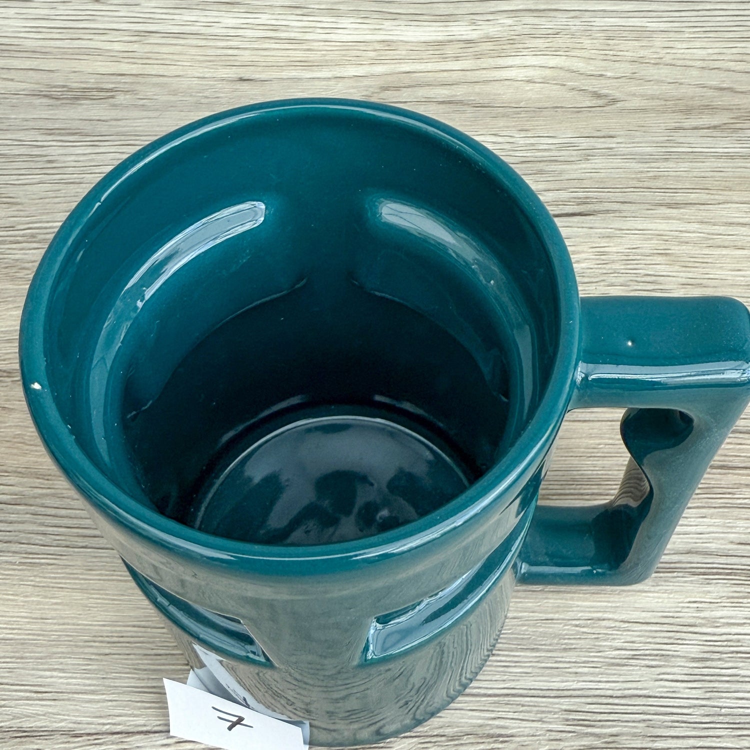 A handmade "Rejected Raktajino Mug" by Quirkify, sitting on a wooden surface. Give one a good home today!.