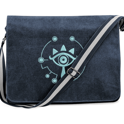 A navy blue Zelda Sheikah messenger bag features glow-in-the-dark embroidery of a stylized eye symbol on the front flap.