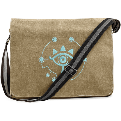 A tan Zelda Sheikah messenger bag features glow-in-the-dark embroidery of a stylized eye symbol on the front flap.