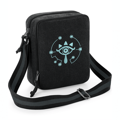 A black crossbody bag features glow-in-the-dark embroidery of a Sheikah eye symbol from The Legend of Zelda.