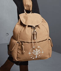 A tan Zelda Sheikah backpack features glow-in-the-dark embroidery of a circular symbol on the front pocket.