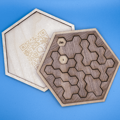 A wooden Daily Calendar Puzzle, featuring a hexagonal perpetual calendar design composed of interlocking hexominoes pieces and a QR code on its lid.