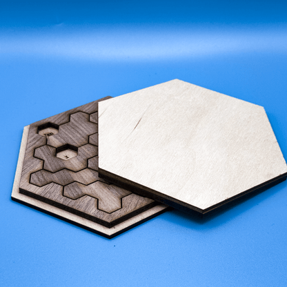 A hexagonal perpetual calendar puzzle featuring interlocking wooden pieces arranged in a hexominoes pattern sits on a blue surface.