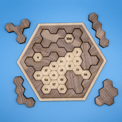 A wooden hexomino puzzle inspired by Star Trek features numbered spaces arranged within a hexagonal frame and six bone-shaped pieces surrounding it.