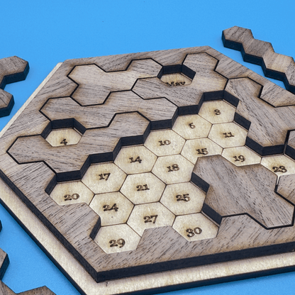 A wooden Star Trek inspired puzzle features numbered hexomino pieces arranged on a hexagonal board to create a date game.