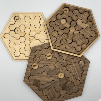 Three wooden hexomino puzzles, inspired by Star Trek, feature month names and dates arranged within their interlocking pieces.