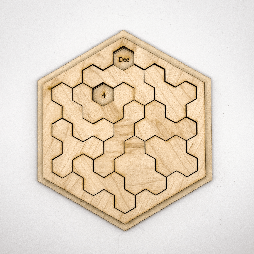 A wooden hexomino puzzle featuring the letters "Dec" and the number "4" is arranged within a hexagonal frame.