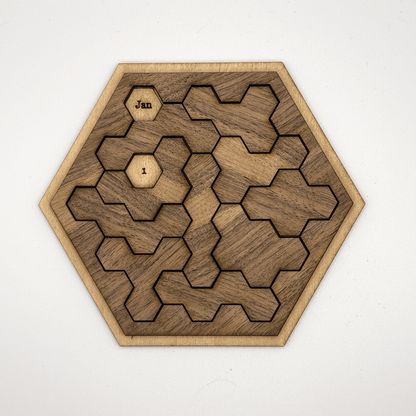 A wooden hexomino puzzle, inspired by Star Trek, features interlocking pieces and labels "Jan" and "I" on two of them.