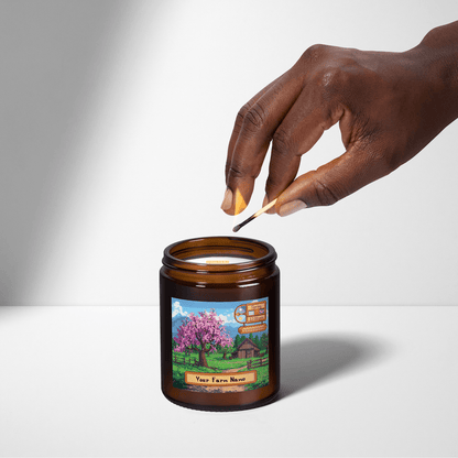 A hand holds a wooden skewer as it dips into a Stardew Valley personalised scented candle featuring an illustration of a farm scene and customizable text.
