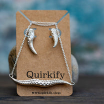 Silver necklace and earrings on a Quirkify branded card with a blurred background