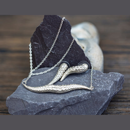 Silver necklace with a tentacle design on a dark stone surface