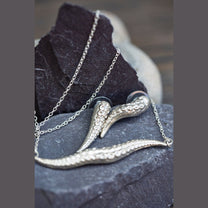 Silver octopus-shaped pendant on a chain against a dark stone background