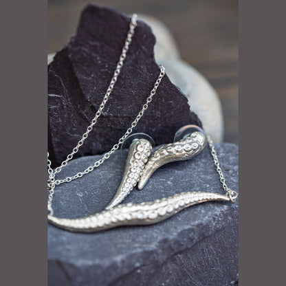 Silver octopus-shaped pendant on a chain against a dark stone background