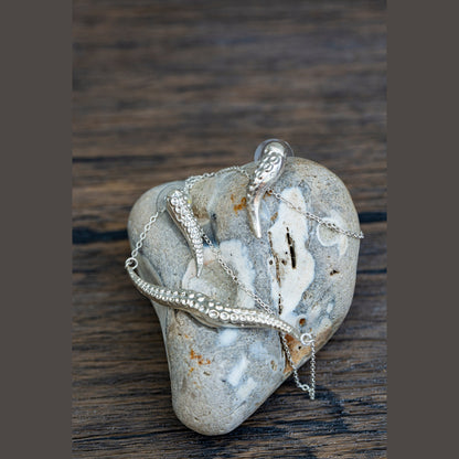 Silver tentacle jewelry on a textured stone surface