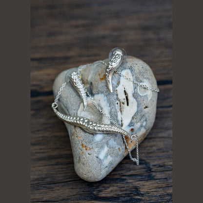 Silver tentacle jewelry on a textured stone surface