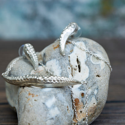 Silver sea tentacle necklace on a textured stone surface with a blurred natural background