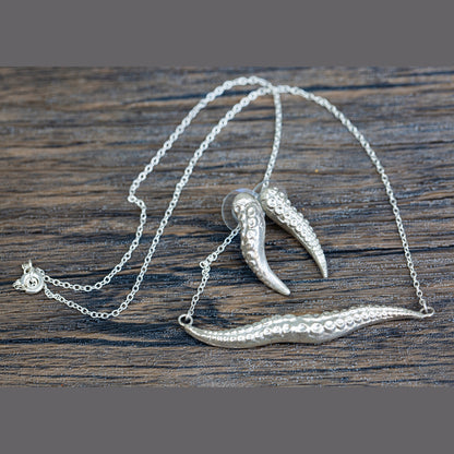 Silver kraken tentacle necklace with pendant on a wooden surface