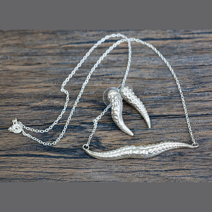 Silver necklace with tentacle pendant on a wooden surface