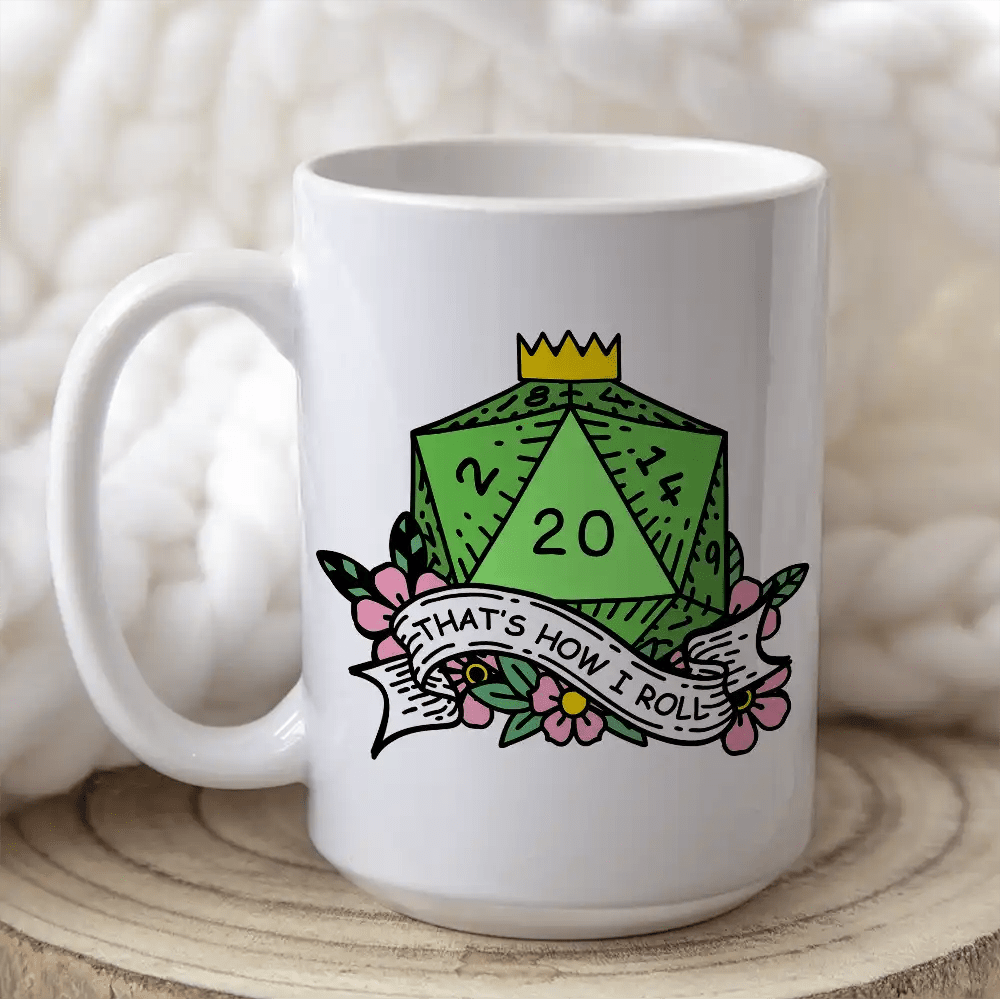 A white mug displays a D&D-themed design featuring a green twenty-sided die (d20) surrounded by flowers and the phrase "That's How I Roll".