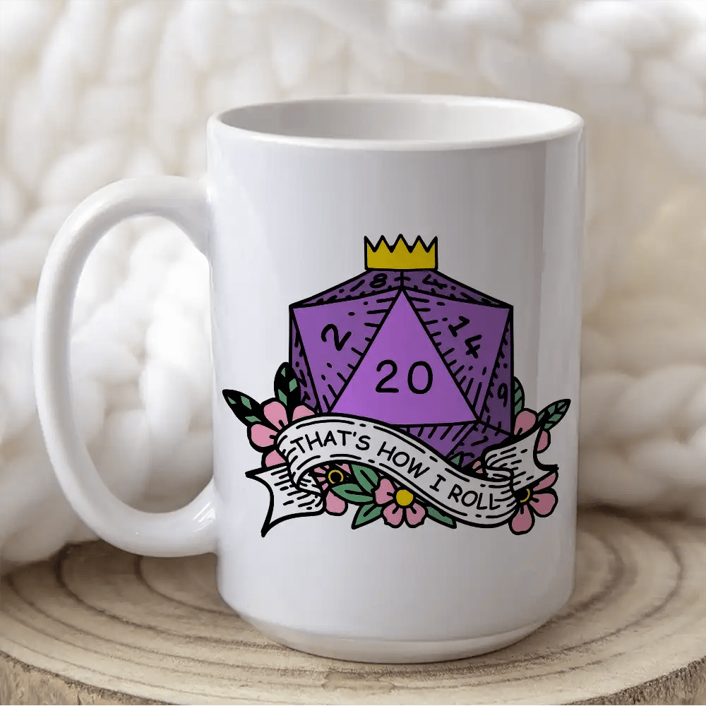 A white mug displays a D&D-themed design featuring a purple twenty-sided die (d20) surrounded by flowers and the phrase "That's How I Roll".