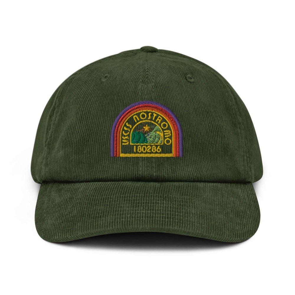 A green corduroy baseball cap features an embroidered logo of the USCSS Nostromo spaceship with a rainbow border and the number 180286.