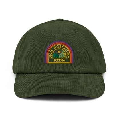 A green corduroy baseball cap features an embroidered logo of the USCSS Nostromo spaceship with a rainbow border and the number 180286.