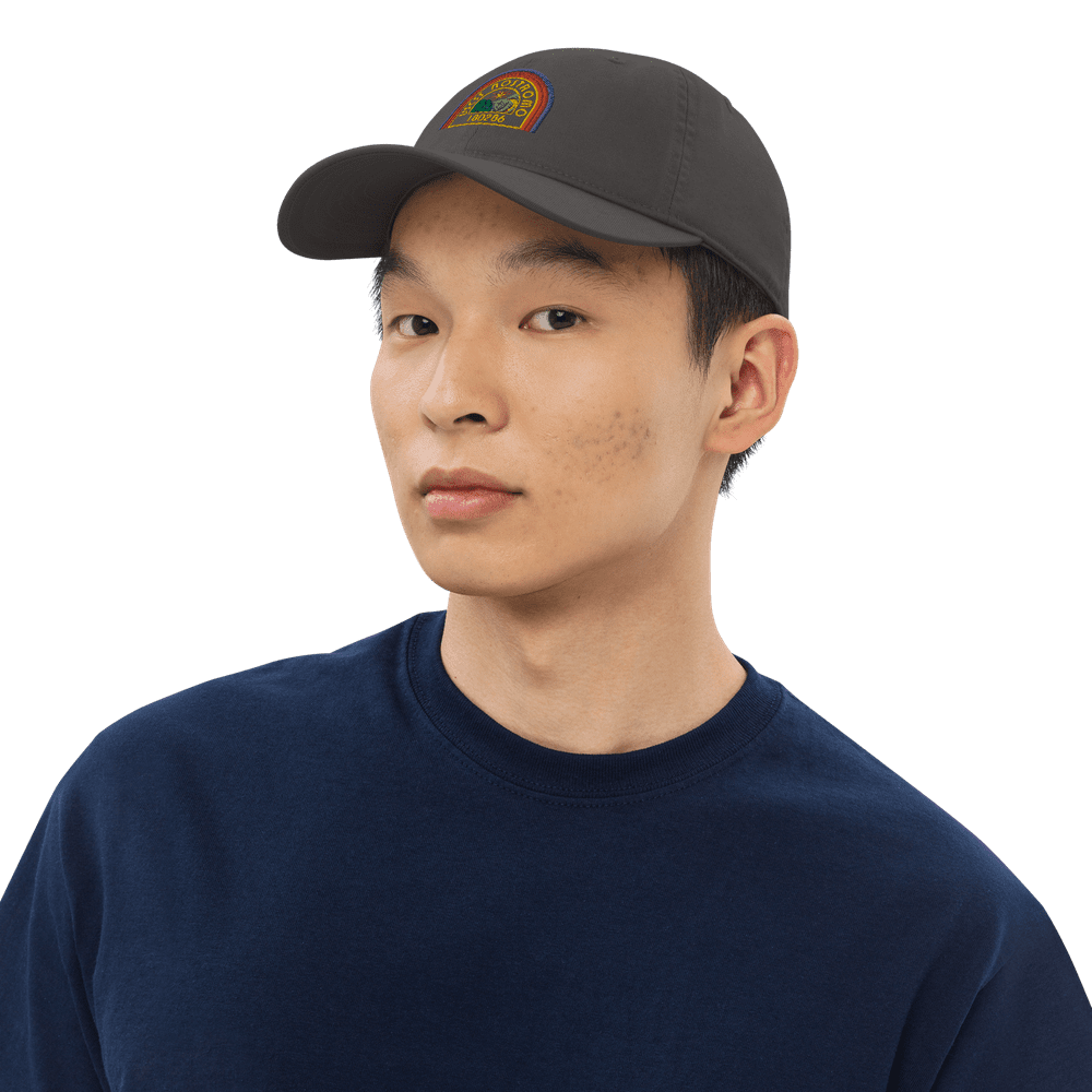 A person wears a gray Alien USCSS Nostromo embroidered dad hat with a rainbow-style logo on the front.
