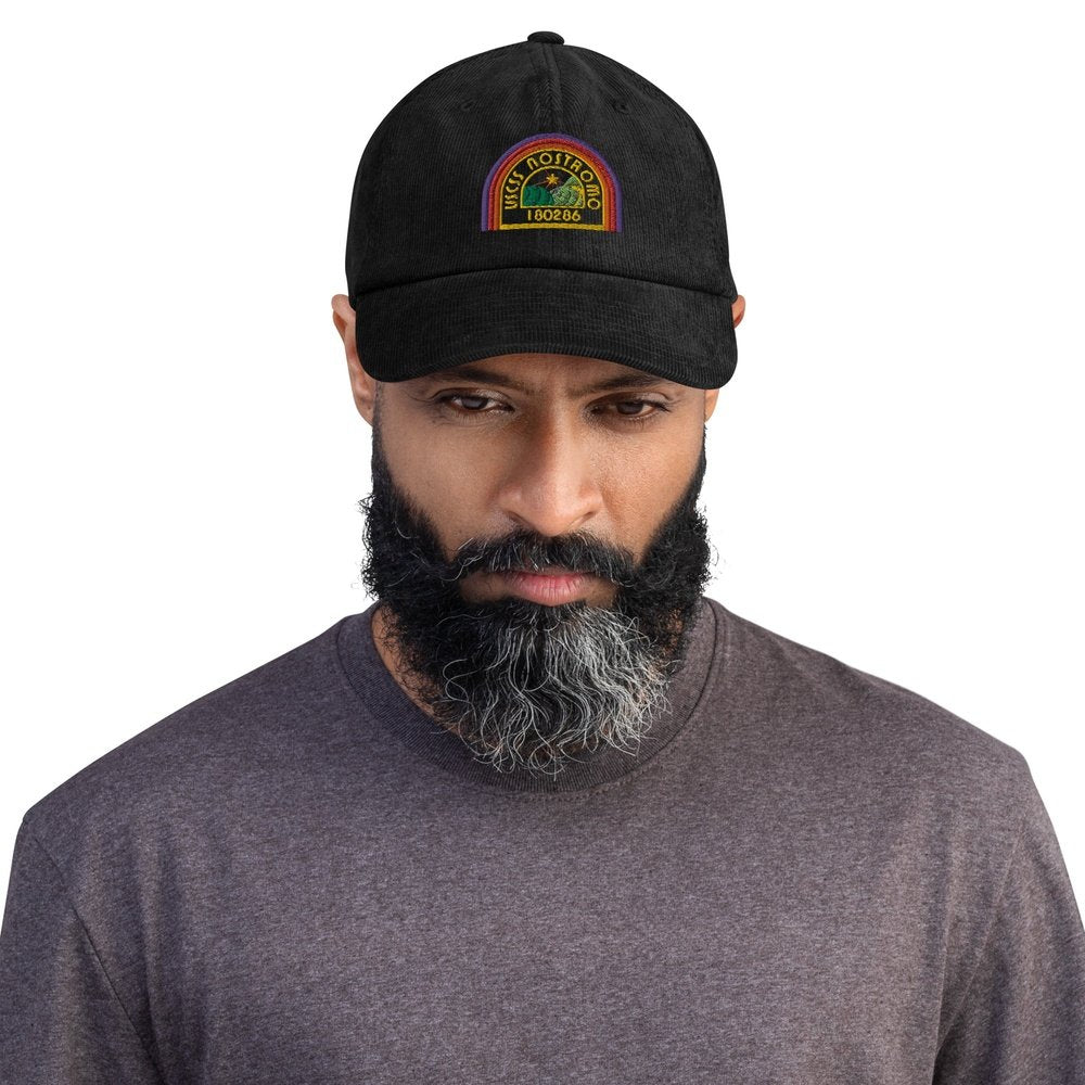 A person wears a black Alien USCSS Nostromo embroidered dad hat featuring a rainbow-style logo on the front.