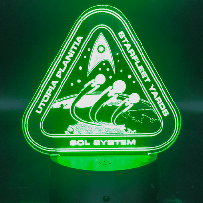 The illuminated acrylic lamp features an engraved design of the Utopia Planitia Starfleet Yards logo with spaceships and the Sol System text.