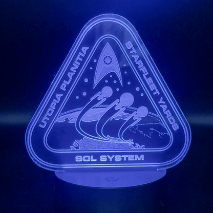 An LED engraved acrylic lamp depicts a Starfleet Yards logo for Utopia Planitia, including spaceships and the Sol System designation.