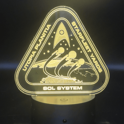 The illuminated acrylic lamp features an engraved design depicting a Starfleet Yards logo with "Utopia Planitia" and "Sol System" text, referencing the Star Trek universe.