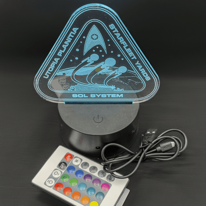 An LED engraved acrylic lamp depicts a triangular sign labeled "Utopia Planitia Starfleet Yard" and "Sol System," referencing the Star Trek universe.