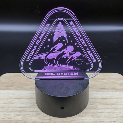 This is a purple LED engraved acrylic lamp depicting the Utopia Planitia Shipyard logo from Star Trek, including text identifying it as Starfleet Yards and referencing the Sol System.