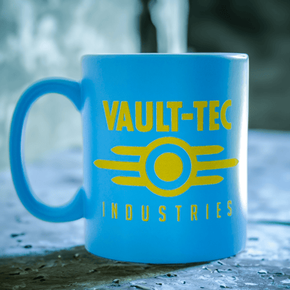 A blue Fallout mug displays the Vault-Tec Industries logo in yellow lettering and a circular design.