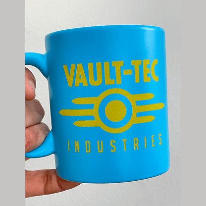 A blue Fallout mug displays the yellow Vault-Tec Industries logo.