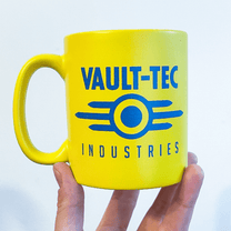 A yellow Fallout mug displays the Vault-Tec Industries logo in blue lettering and design.