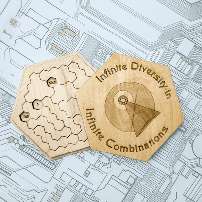 Two wooden hexomino puzzle pieces, inspired by Star Trek, feature engraved dates and a design reading "Infinite Diversity in Combinations.