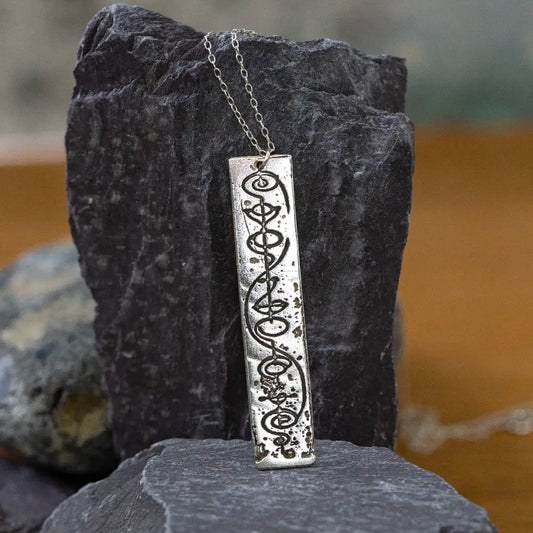 Vulcan IDIC silver necklace against rocks, Star Trek inspired