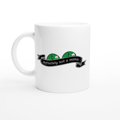 A white mug displays a green D&D mimic face peeking out from behind a banner that reads "definitely not a mimic.