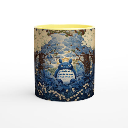A cylindrical mug depicts Totoro from Studio Ghibli sitting amongst a blue and white cherry blossom forest in a chinoiserie style.