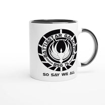 A white ceramic mug features a black rim and handle, displaying the Battlestar Galactica logo with "BSG 75" and "So Say We All" printed around it.