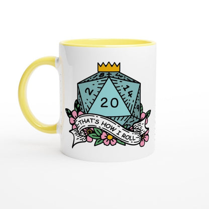 A white mug with a yellow handle and rim features an illustration of a D20 die adorned with flowers and a banner reading "That's How I Roll," referencing D&D humor and critical fails.
