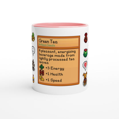 A white mug displays a Stardew Drinks pattern featuring a green tea beverage card with pixelated sprites and icons representing energy, health, and speed.