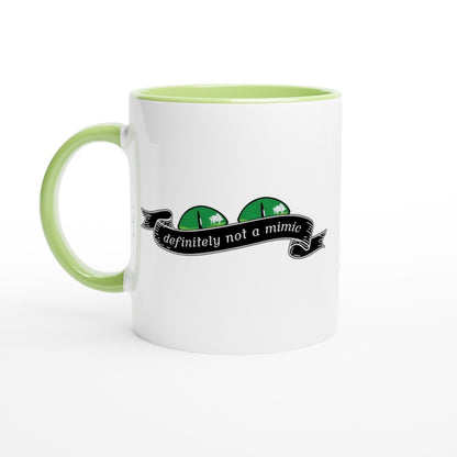 A white mug with a green handle and rim features a cartoon illustration of a D&D mimic creature with the words "definitely not a mimic" displayed on a banner.